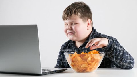 Young fat boy eats chips and watching cartoons on a laptop 50 fps 4k
