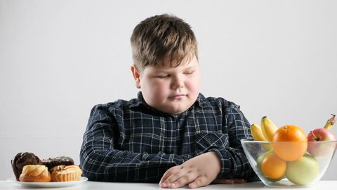 Young fat boy chooses fruit instead of cakes 50 fps 4k