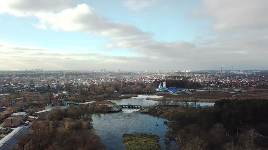 Beautiful orthodox church on the bank of the river Klyazma in the city of Noginsk. Picturesque surroundings with a dam on the river. Sunny autumn day.