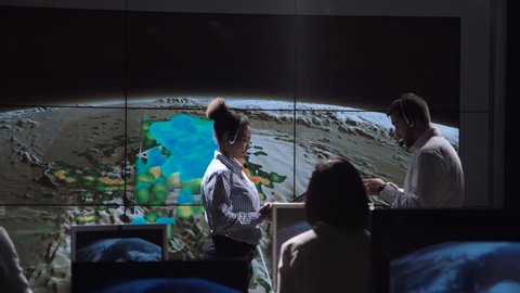 Group of professional meteorologists coworking in office and tracking hurricane monitoring it on map. Elements of this image furnished by NASA.