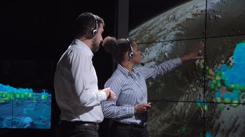 Group of two scientists observing and tracking hurricane on map and analyzing weather. Elements of this image furnished by NASA.