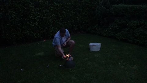 A New Zealander man launching fireworks explosive pyrotechnic in slow motion in home back yard in Auckland New Zealand.  Real people. Copy space