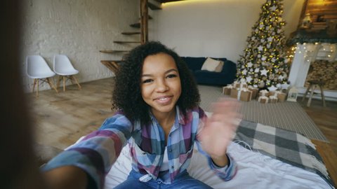 Young african american girl chatting online conversation using smartphone camera at home on Christmas