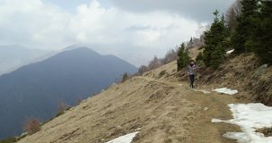 Athlete man running through snowy path.Following front.Real people adult trail runner sport training in autumn or winter in wild mountain outdoors nature, bad foggy weather.4k video