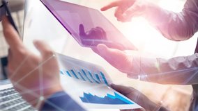 Two colleagues working on global financial strategy using tablet and laptop.Modern business team innovation concept.Office project meeting with virtual graph data interface.4k cinemagraph chart video - Powered by Shutterstock - Get 15% off with code: PIKWIZARD15