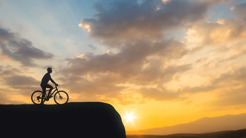 The man with a bike stand on a mountain on a sunset background. time lapse