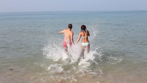 young happy couple running to the sea on the beach, summer getaway holidays travel 