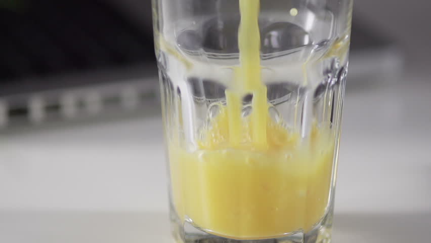 Slow Motion Shot Of Orange Juice Pouring Into A Glass
