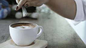 Closeup of lady pouring sugar while preparing hot coffee cup