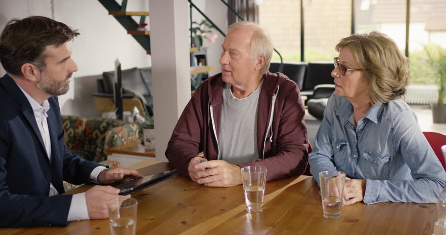 Financial advisor typing data of senior couple in tablet