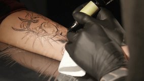 Tattoo artist make tattoo in studio, tattooing on the body. close up.