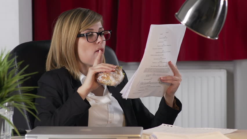 Young Businesswoman Working And Eating Sandwich 
