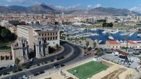 Urban aerial bird view footage of Palermo city showing Porta Felice a monumental city gate and also showing Palermo marina in further background traffic driving over road popular tourist attraction 4k