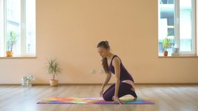 A professional yoga instructor demonstrates a set of healing efforts to strengthen the muscles of the back. Multiseries video. Young attractive brunette girl is engaged in a bright hall on a