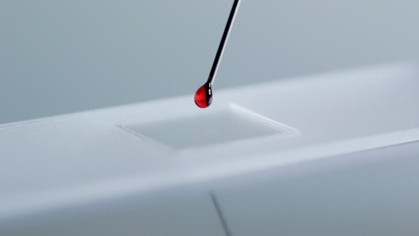 Close up of dropping blood onto microscope slide