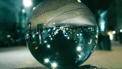 Night city street traffic reflecting upside down in the glass ball