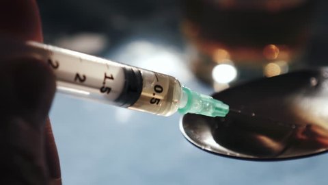 Filling syringe with heroin from a spoon