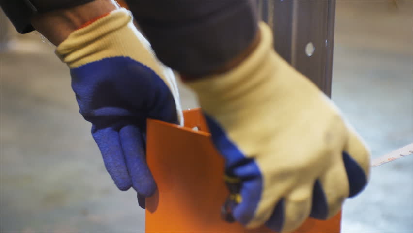 closeup person in working gloves measures distance between metal construction parts in large warehouse