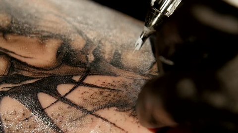Tattoo artist make tattoo in studio, tattooing on the body. close up