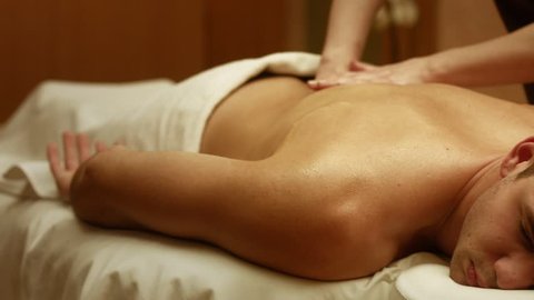 Shot of a professional masseuse massaging back and shoulders of a male client. Man receiving full body massage at spa relaxing rest wellness resort wellbeing pampering enjoying occupation service
