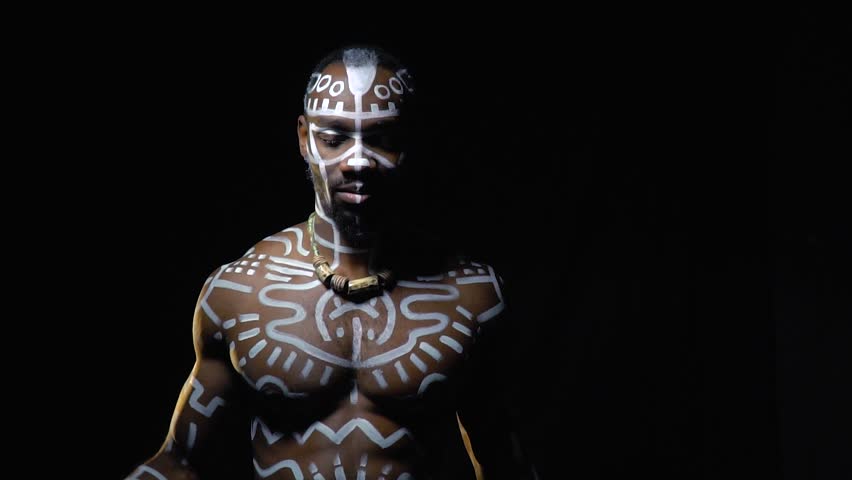 A strong Papuan with white patterns on his body dances in the dark