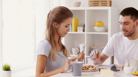 eating and people concept - happy couple having breakfast at home and sharing food