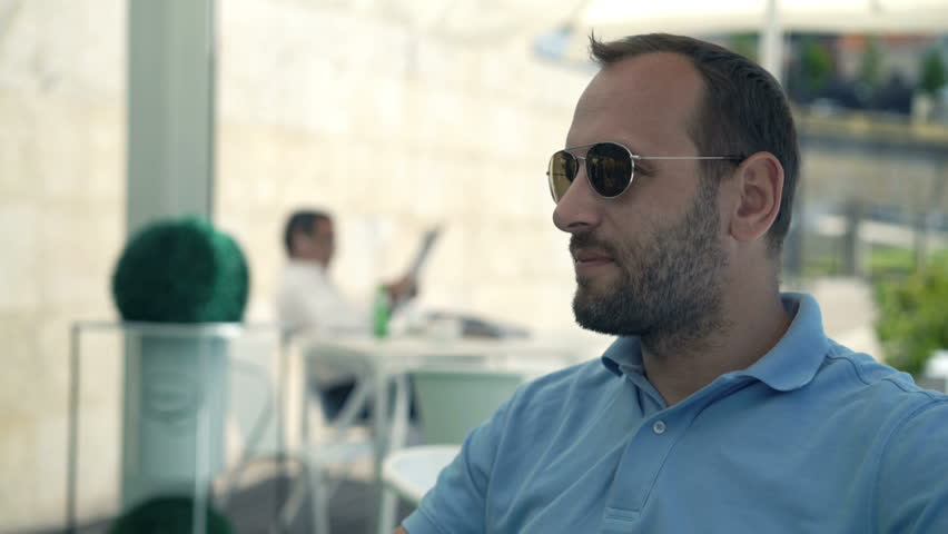 Young man talking on cellphone sitting in cafe in city
