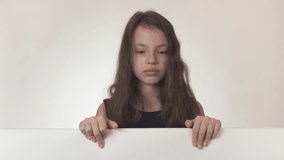 Beautiful girl teenager looks at a poster with information and expresses frustration and resentment on a white background stock footage video.