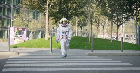 An astronaut just landed from space, on the new planet, walks in the middle of a road to explore the new world and live there. Concept of: success road, dreams, astronaut, inspiration.