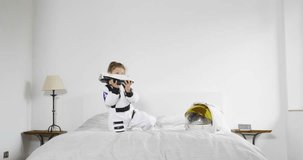 Portrait of a little girl dressed up by astronaut playing with shuttle and smiling while watching the camera. Concept of: ambition, success, children and their future.