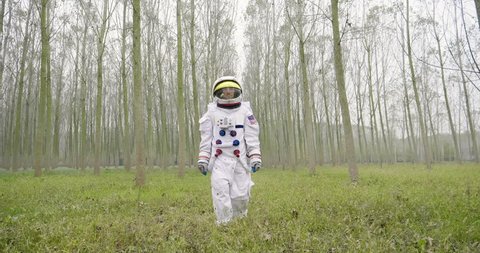 An astronaut just landed from space, on the new planet, walks in the forest to explore the new world and live there. Concept of: success road, dreams, astronaut, inspiration