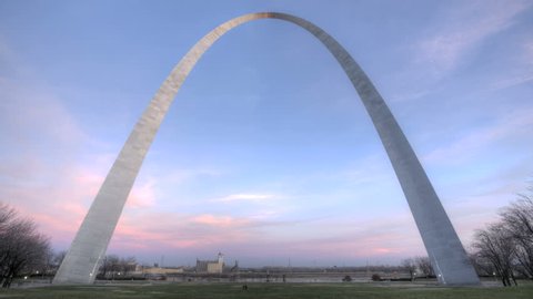 ST. LOUIS, MO - NOV 28: Timelapse St. Louis Arch with dramatic clouds and red and pink color during sunset and tourists walking in front of the arc on November 28, 2012 in St. Louis, USA