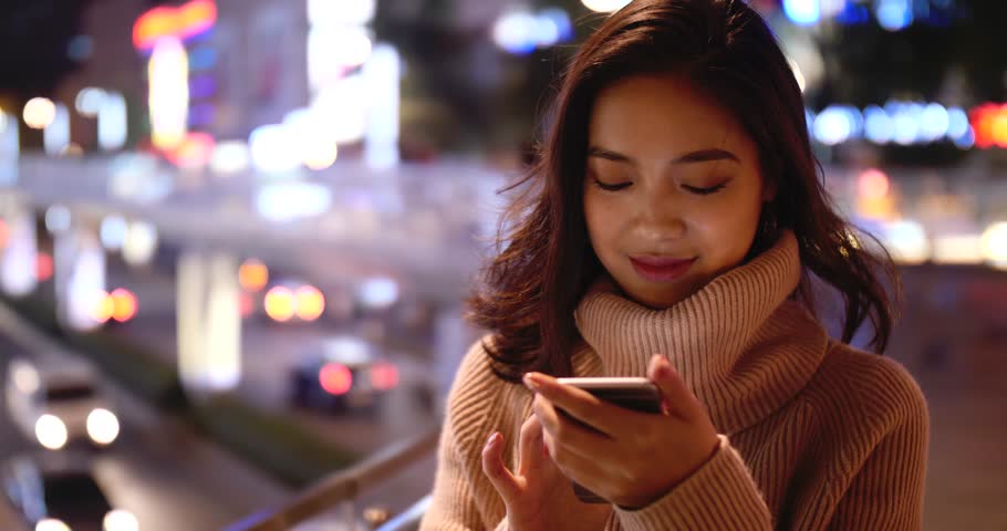 young asian woman using smartphone in the street at night 