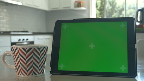 Tablet held by hands. Green screen Chroma Key. Close up. Tracking motion. Horizontal. POV, modern kitchen, day, Swipe left / right animation. Coffee / Tee
