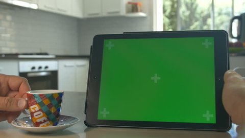 Tablet held by hands. Green screen Chroma Key. Close up. Tracking motion. Horizontal. POV, modern kitchen, day, Swipe left / right animation. Coffee / Tee