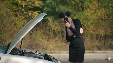 Woman with broken car calling by the phone