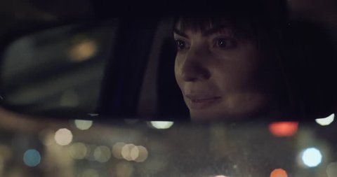 Cinematic shot of a happy woman driving at night.