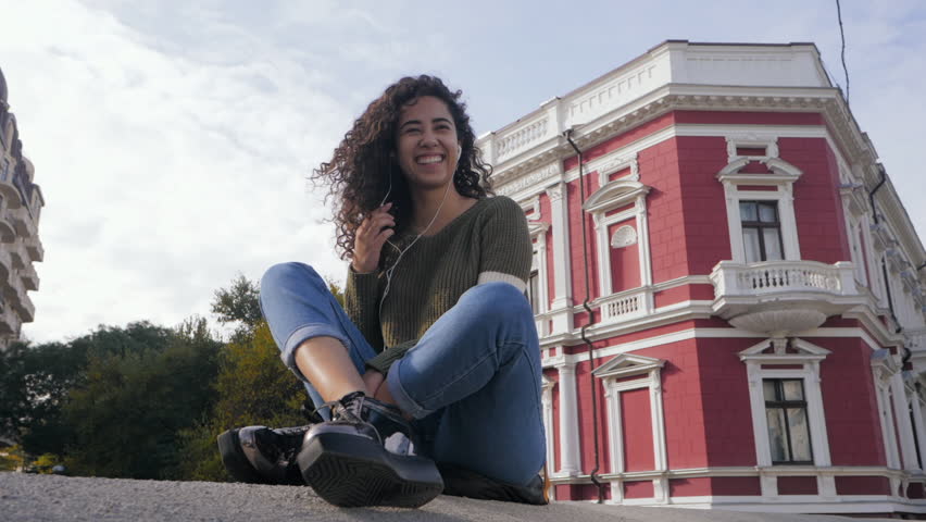 curly hair afro girl listening to music on mobile