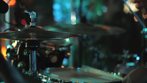 Young man playing  drums on stage. Concert. Neon light. Live music background. Drum kit on stage lights performance.Festival and show background. Slow motion