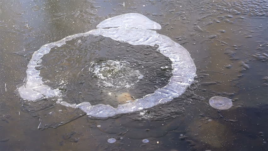 Stone throwing in frozen lake, bubbles are visible under the water