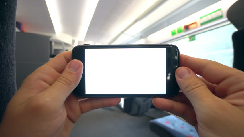 Hands holding (using) a smapthone with a white screen on the train. Close-up shot