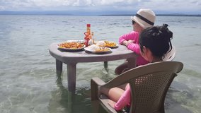 Mother and daughter ready to eat on a table in the beach