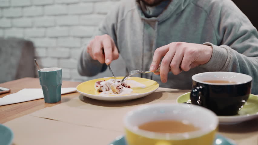 Unrecognizable girl eating dessert strudel at the restaurant using fork and knife