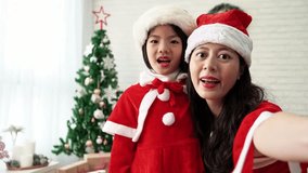 mother and her daughter girl using the smartphone to make a live video to speak greetings for merry Christmas.