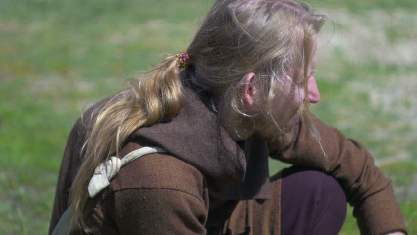 Man with long hair sitting on the ground close up