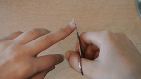 Women's hands are trimmed nails with nail scissors. Manicure at home.
