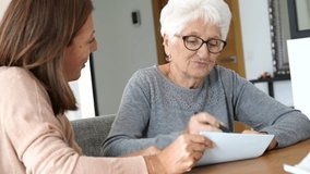 Home assistant helping elderly woman with paper work