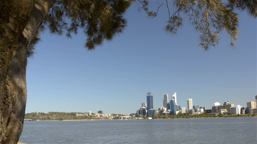 Tracking shot revealing the view of Perth City, from behind a tree, across the