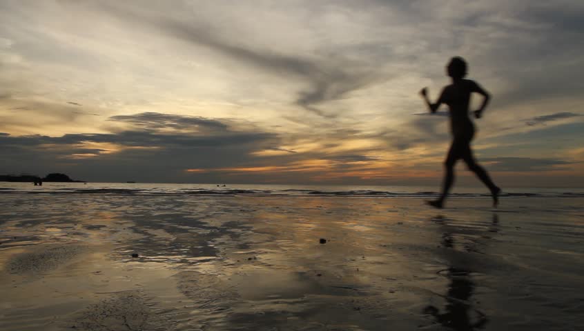 Silhouette running woman jogging at evening beach