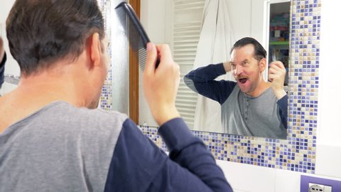 man in front of mirror singing and combing hair funny
